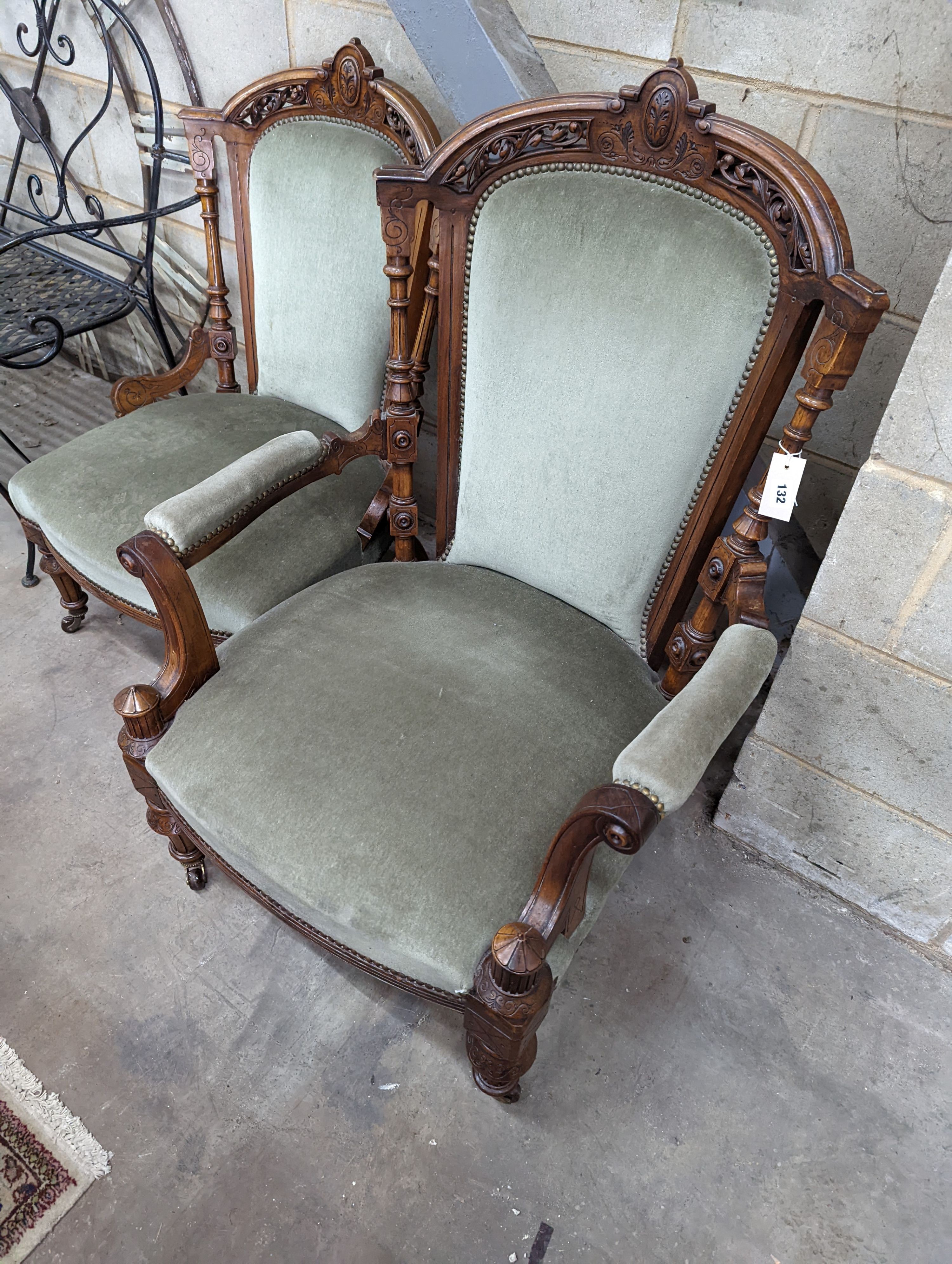 A pair of late Victorian carved walnut salon chairs upholstered in green dralon, one with arms